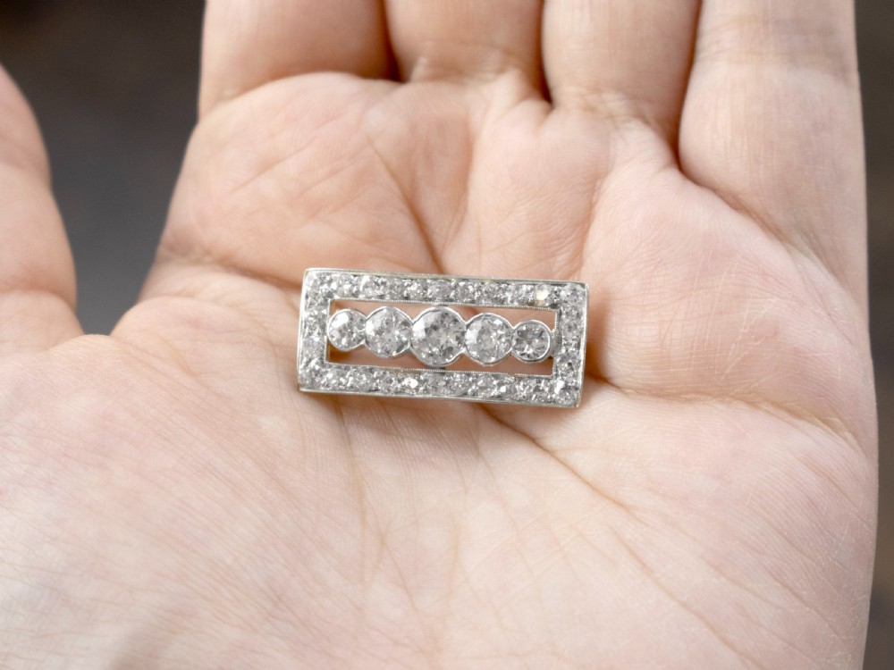 An Art Deco rectangular diamond brooch with a central row of five graduated diamonds set inside a diamond-bordered openwork frame. View III
