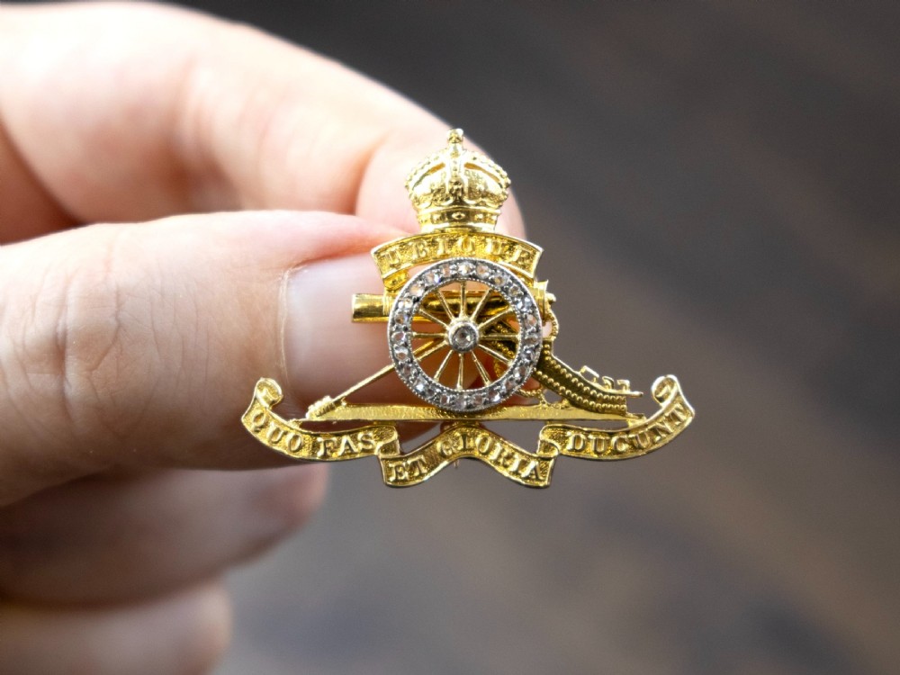 An 18ct yellow gold Royal Artillery brooch featuring a diamond-set gun wheel, crowned cannon motif, and Latin motto ribbons. View IV