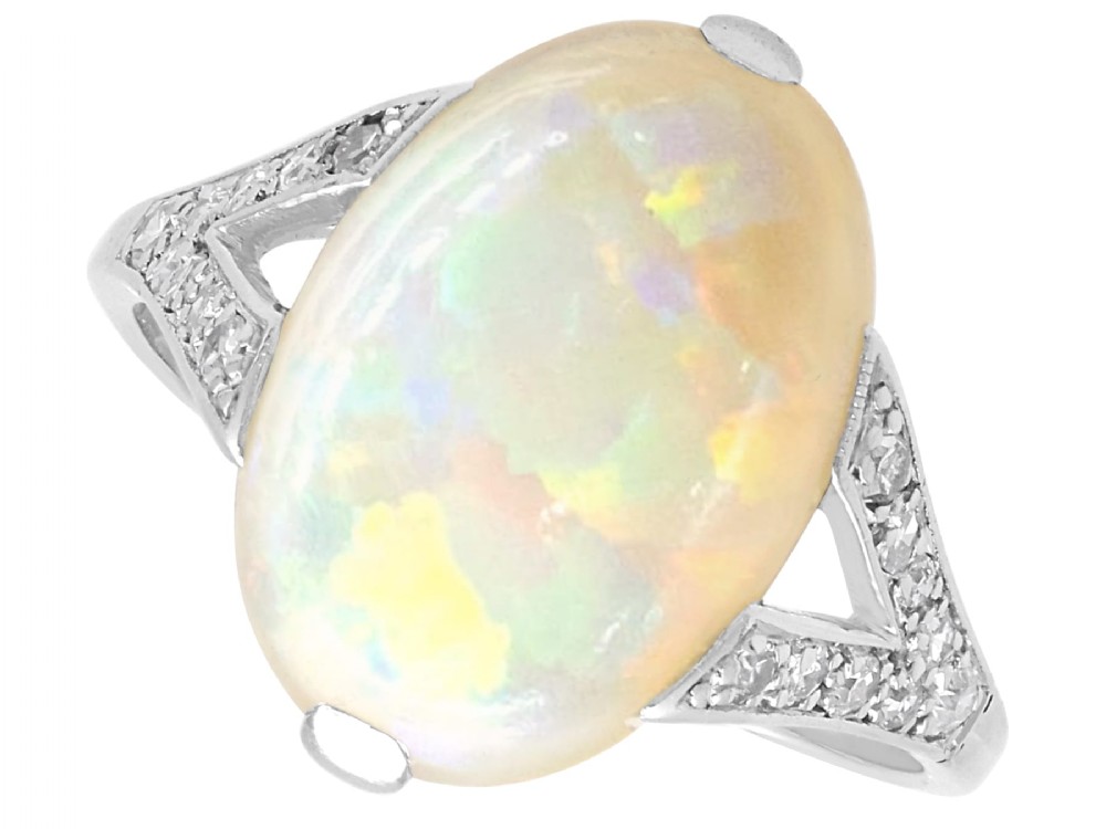 An Art Deco 18ct white gold ring featuring a central oval cabochon white opal flanked by geometric diamond-set shoulders.