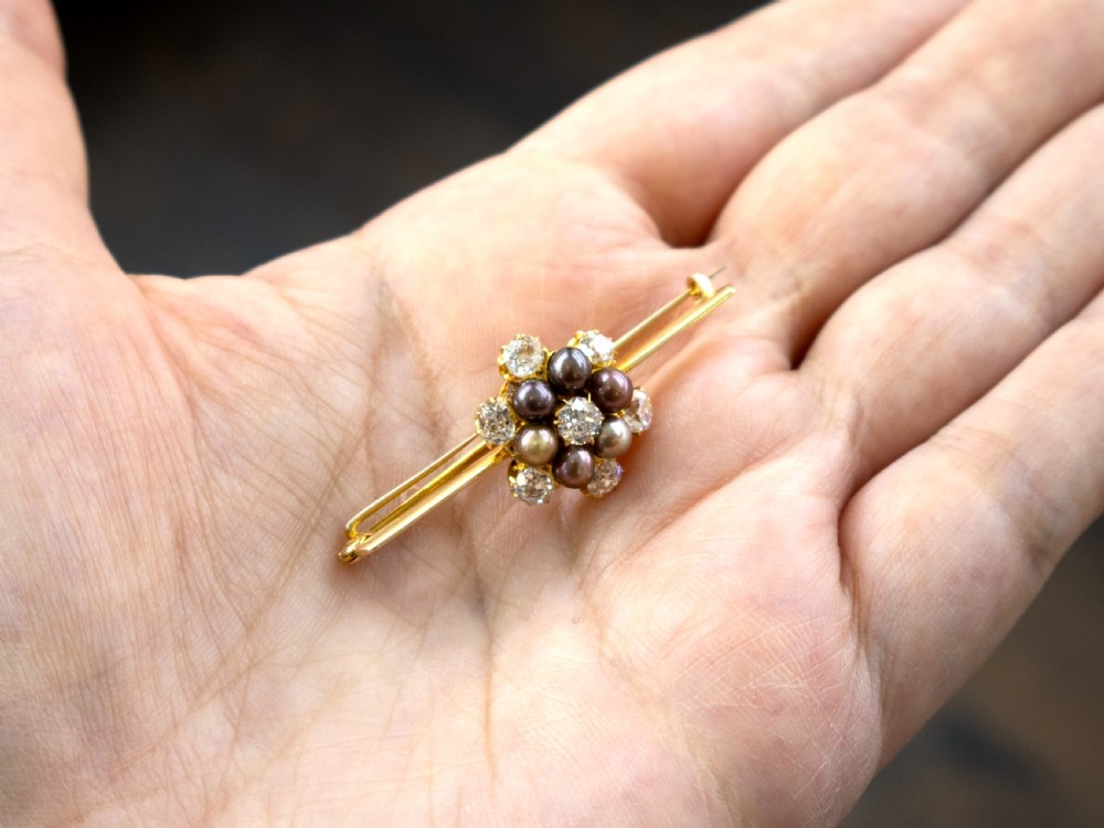 An antique 15ct yellow gold bar brooch featuring a central floral cluster set with dark pearls and old-cut diamonds. View III