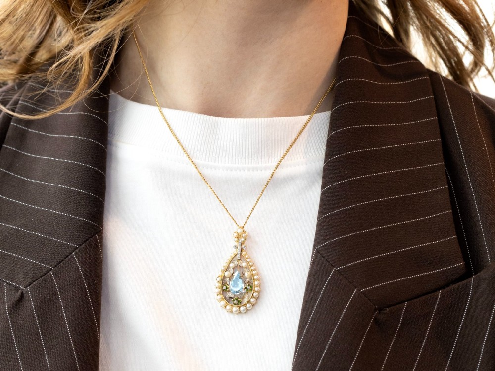 An openwork Edwardian 14ct yellow gold pendant set with a central pear-cut aquamarine surrounded by seed pearls, diamonds, and green demantoid garnets. View III