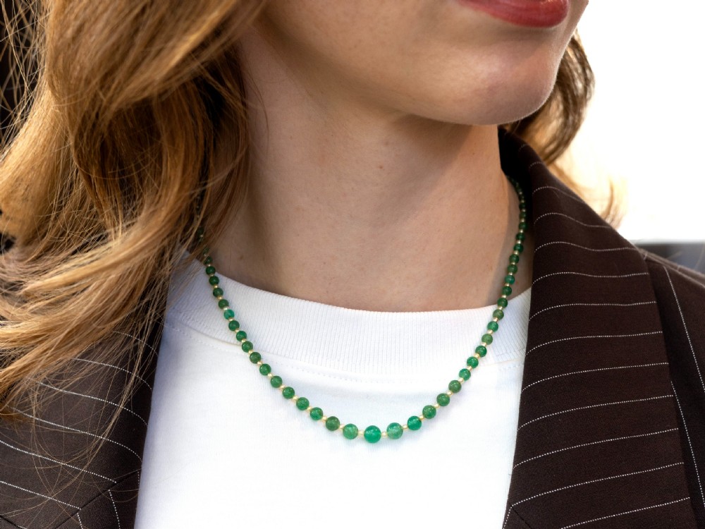 An antique single strand necklace displaying alternating green emerald beads and cream pearls connected to a geometric platinum and diamond clasp. View V
