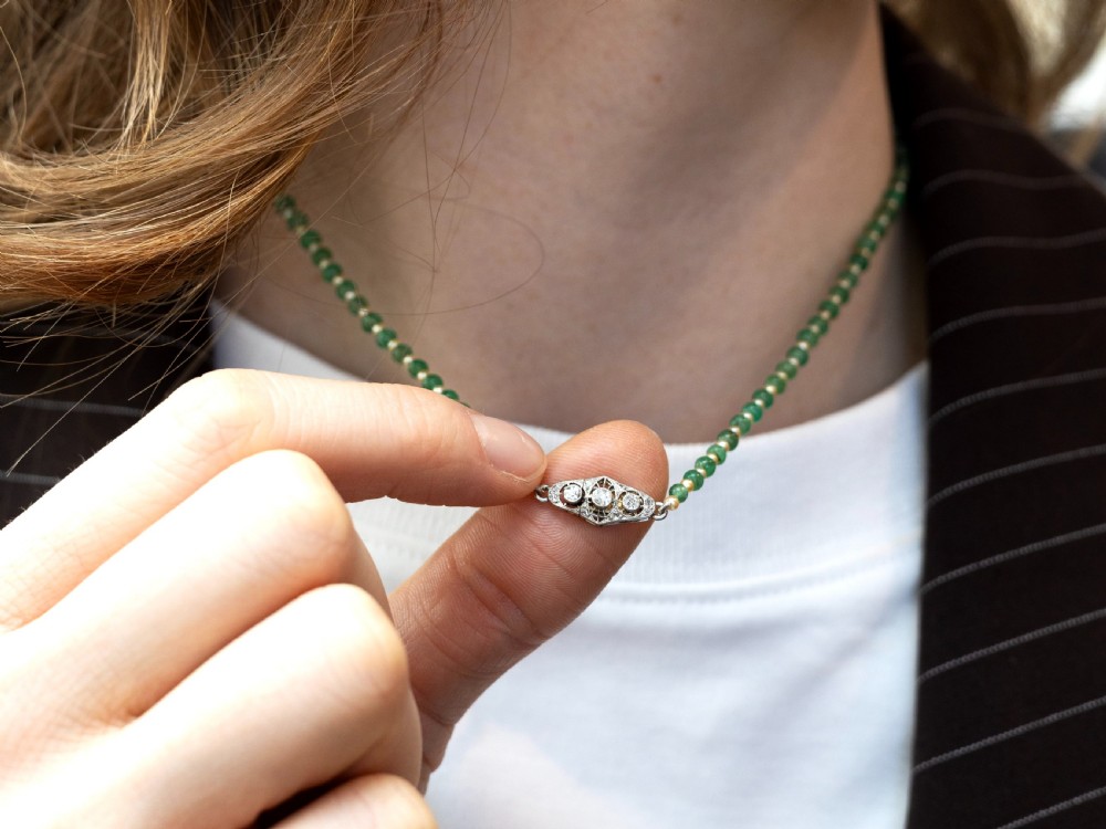 An antique single strand necklace displaying alternating green emerald beads and cream pearls connected to a geometric platinum and diamond clasp. View VII
