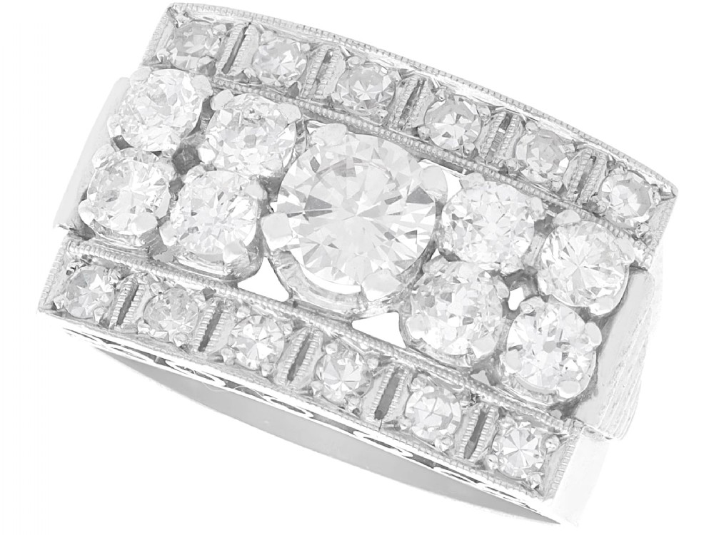 An Art Deco platinum dress ring featuring a central round diamond bordered by multiple smaller old-cut diamonds in a geometric rectangular mount with millegrain edges.