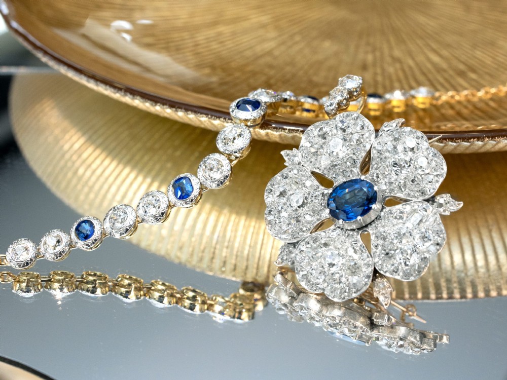 An Art Deco 18ct yellow gold line bracelet set with alternating oval blue sapphires and round diamonds featuring engraved bezel borders. View IX