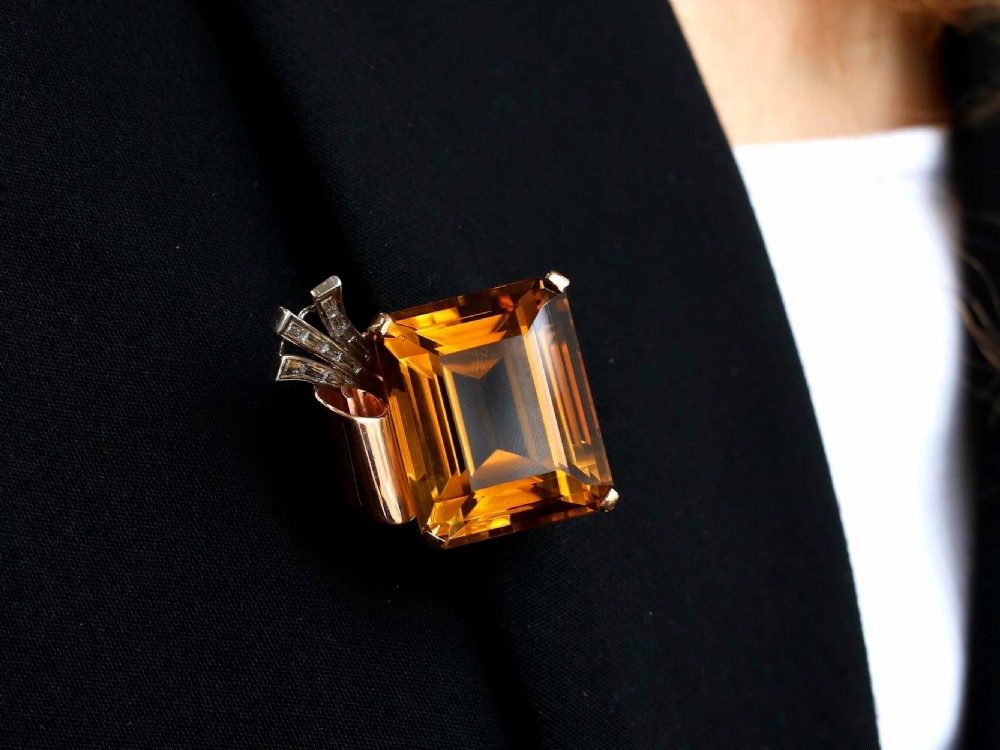 A large emerald-cut amber citrine stone set in a 14ct yellow gold brooch mounting accented with baguette diamonds. View IV