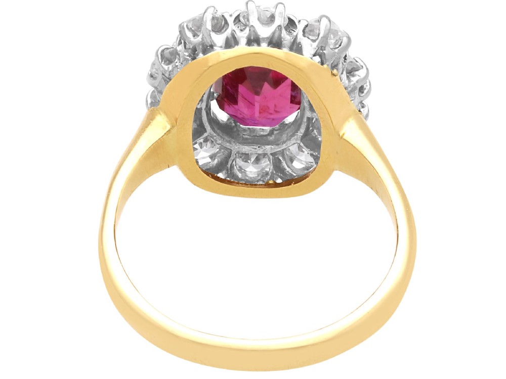 An antique 18ct yellow gold ring featuring a central oval red ruby set within a cluster halo of round white diamonds. View VII