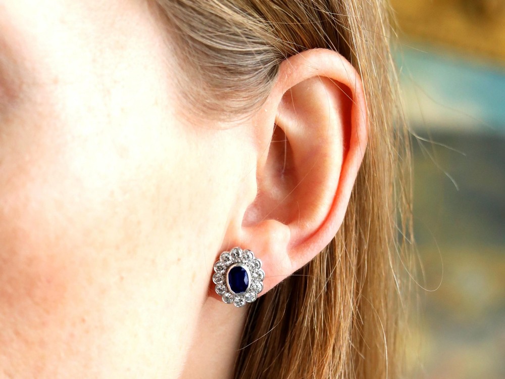 Pair of 1930s 18ct white gold cluster earrings featuring oval blue sapphire centerpieces framed by halos of round diamonds. View VII