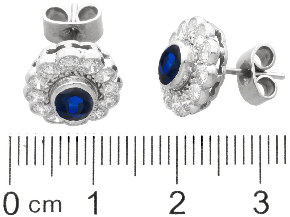 Pair of 1930s 18ct white gold cluster earrings featuring oval blue sapphire centerpieces framed by halos of round diamonds. View XI