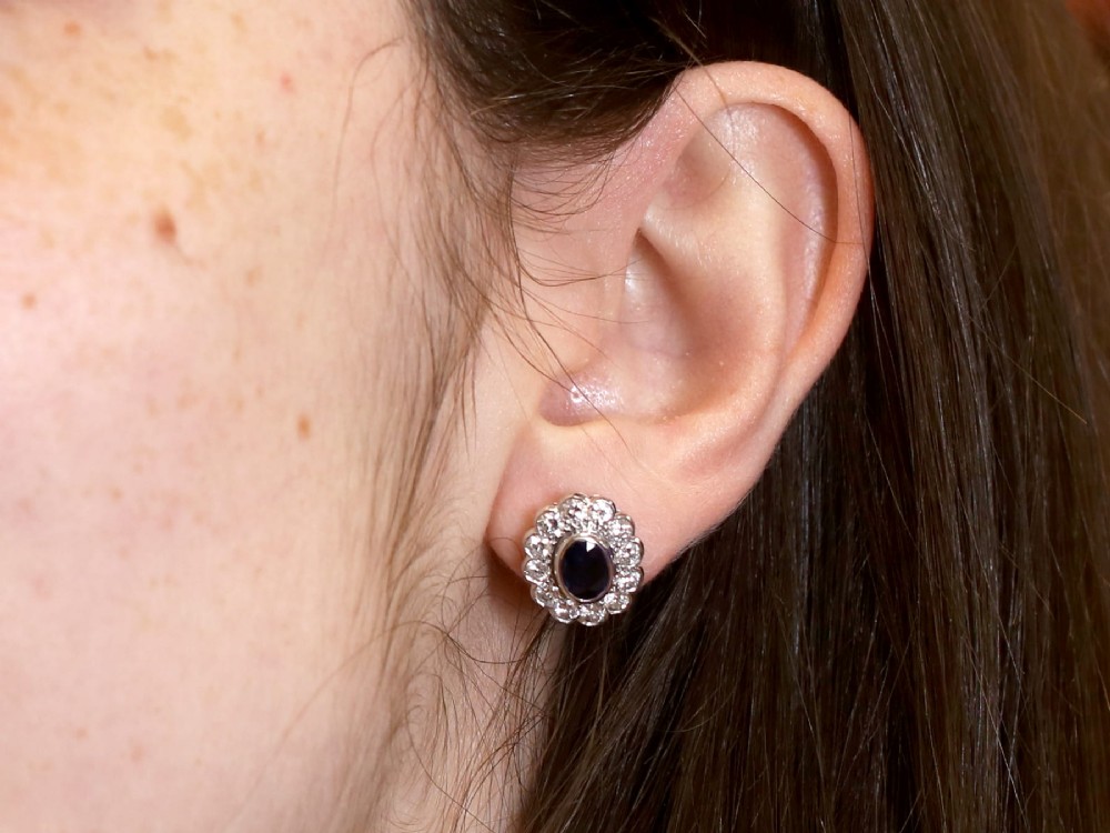 Pair of 1930s 18ct white gold cluster earrings featuring oval blue sapphire centerpieces framed by halos of round diamonds. View XII