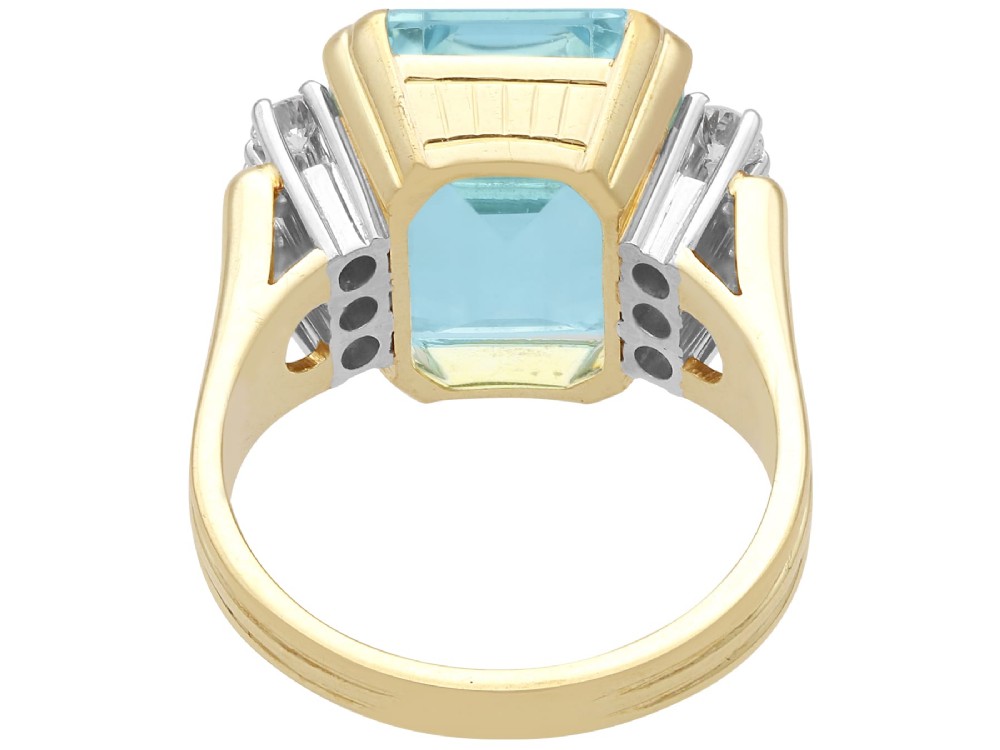 A 14ct yellow gold dress ring featuring a large emerald-cut light blue aquamarine central gemstone flanked by six round diamonds. View IX