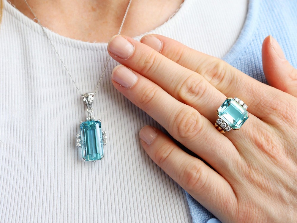 A vintage 18ct white gold pendant featuring a large emerald-cut light blue aquamarine framed by accent diamonds, suspended from an engraved bail. View VII