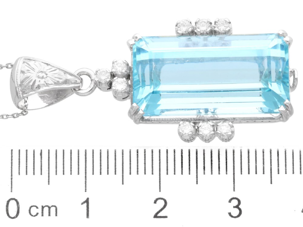 A vintage 18ct white gold pendant featuring a large emerald-cut light blue aquamarine framed by accent diamonds, suspended from an engraved bail. View X