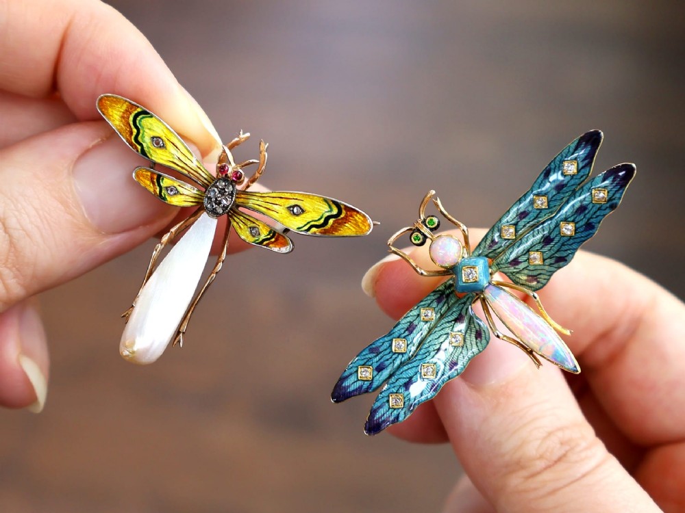 An antique late Victorian dragonfly brooch crafted in yellow gold with yellow enamel wings, garnet eyes, rose-cut diamond accents, and a elongated natural pearl abdomen. View V