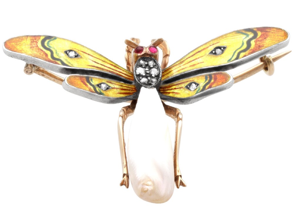 An antique late Victorian dragonfly brooch crafted in yellow gold with yellow enamel wings, garnet eyes, rose-cut diamond accents, and a elongated natural pearl abdomen. View VIII