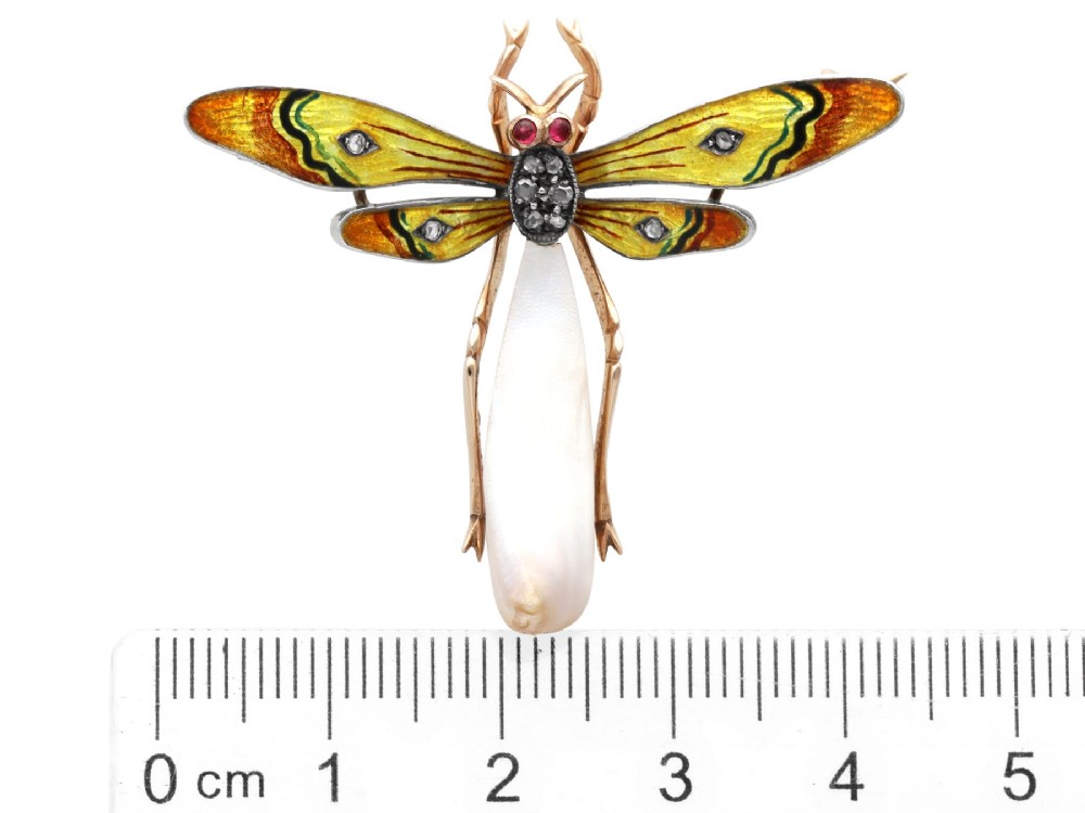 An antique late Victorian dragonfly brooch crafted in yellow gold with yellow enamel wings, garnet eyes, rose-cut diamond accents, and a elongated natural pearl abdomen. View XI