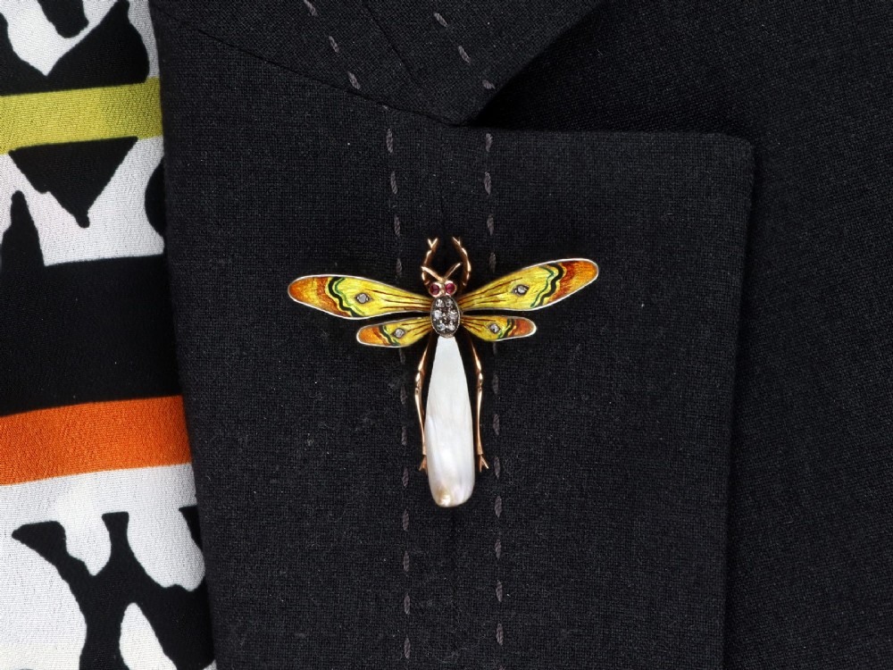 An antique late Victorian dragonfly brooch crafted in yellow gold with yellow enamel wings, garnet eyes, rose-cut diamond accents, and a elongated natural pearl abdomen. View XIII