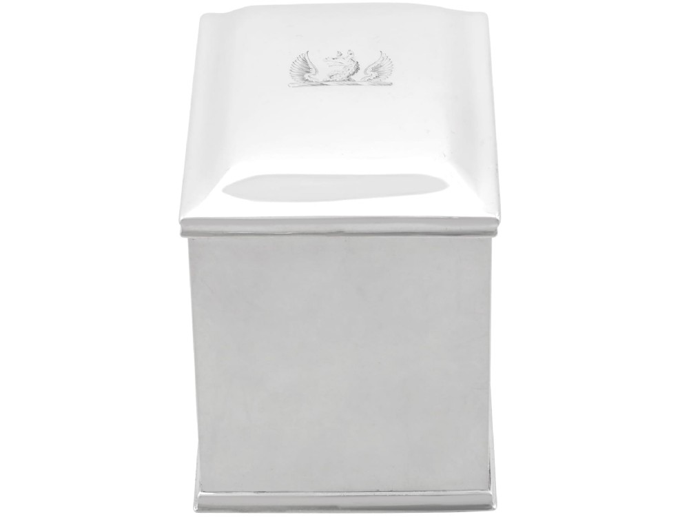 A rectangular George III sterling silver tea caddy featuring a fitted cover engraved with a heraldic crest and stepped moulded borders along the base and top. View III