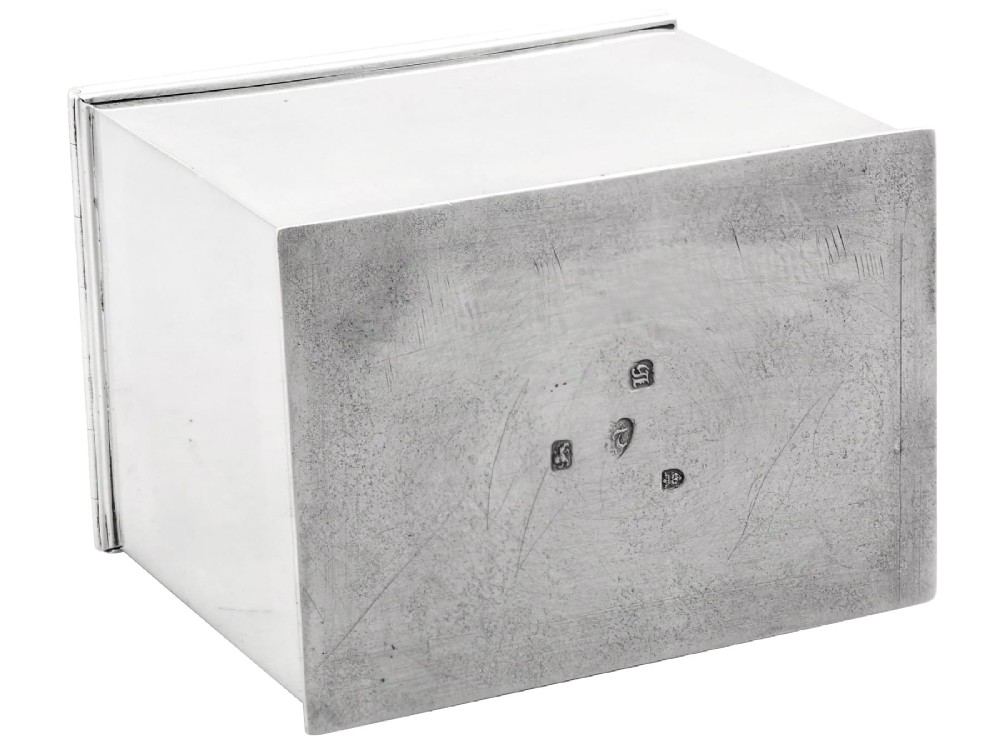 A rectangular George III sterling silver tea caddy featuring a fitted cover engraved with a heraldic crest and stepped moulded borders along the base and top. View IX