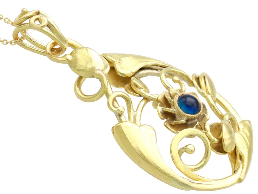 An openwork Art Nouveau 14ct yellow gold pendant featuring botanical leaf motifs surrounding a central bezel-set blue sapphire. View VII