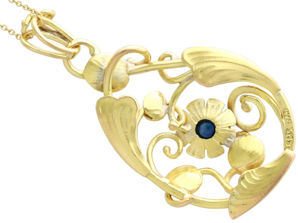 An openwork Art Nouveau 14ct yellow gold pendant featuring botanical leaf motifs surrounding a central bezel-set blue sapphire. View VIII
