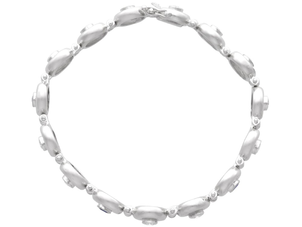 A vintage 18ct white gold articulated link bracelet set with alternating bezel-mounted round diamonds and blue sapphires. View VI