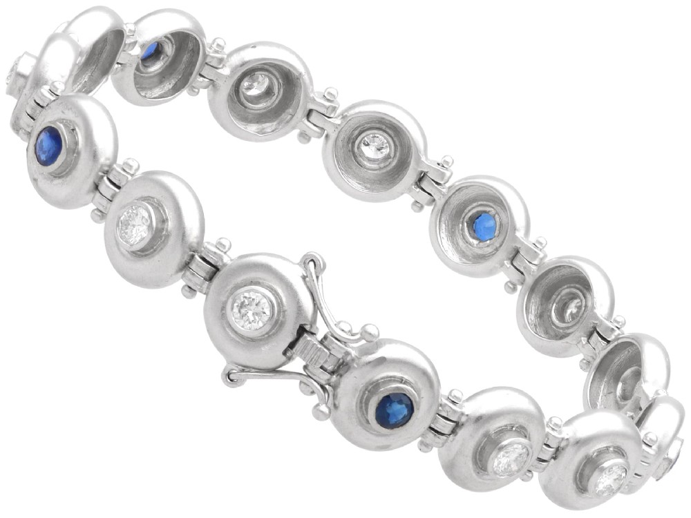 A vintage 18ct white gold articulated link bracelet set with alternating bezel-mounted round diamonds and blue sapphires. View IX