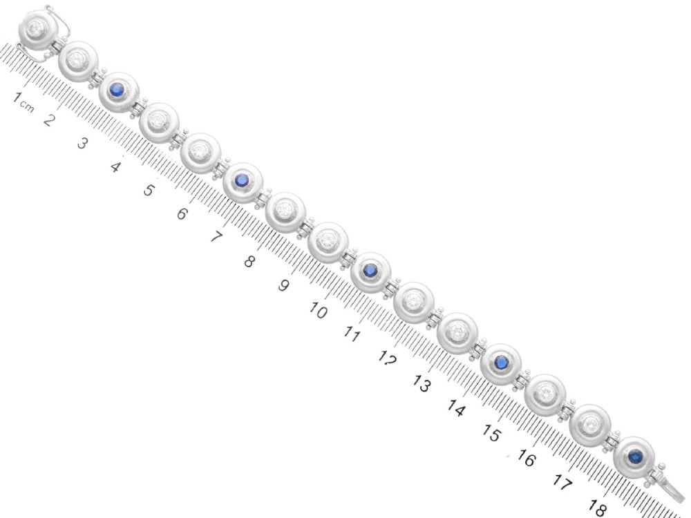 A vintage 18ct white gold articulated link bracelet set with alternating bezel-mounted round diamonds and blue sapphires. View XI