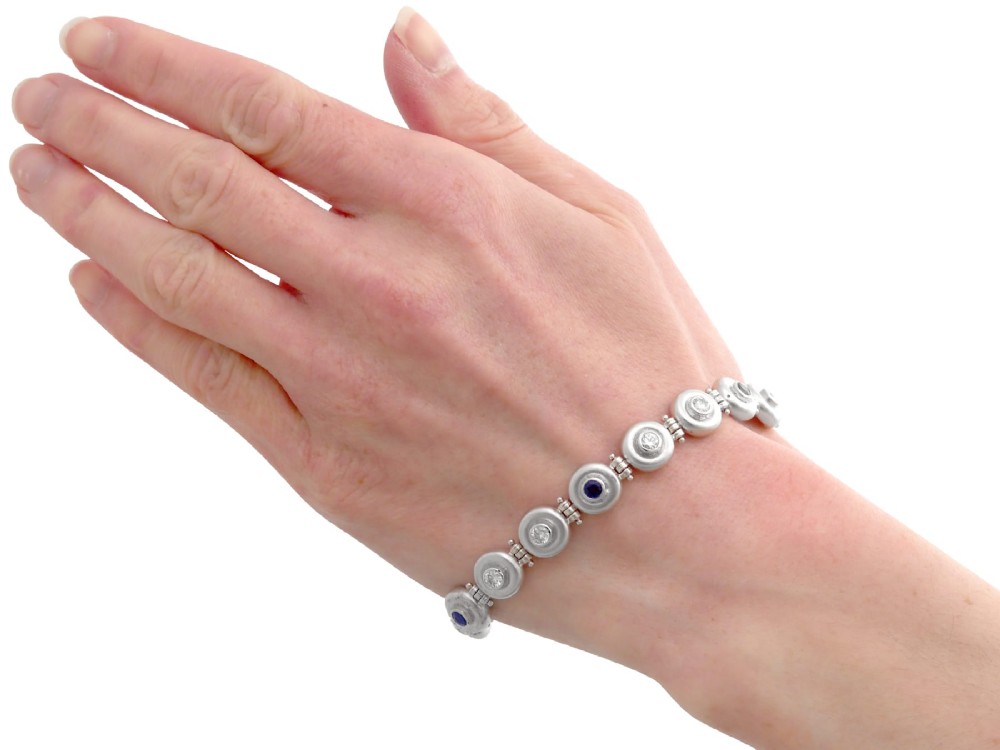 A vintage 18ct white gold articulated link bracelet set with alternating bezel-mounted round diamonds and blue sapphires. View XIII