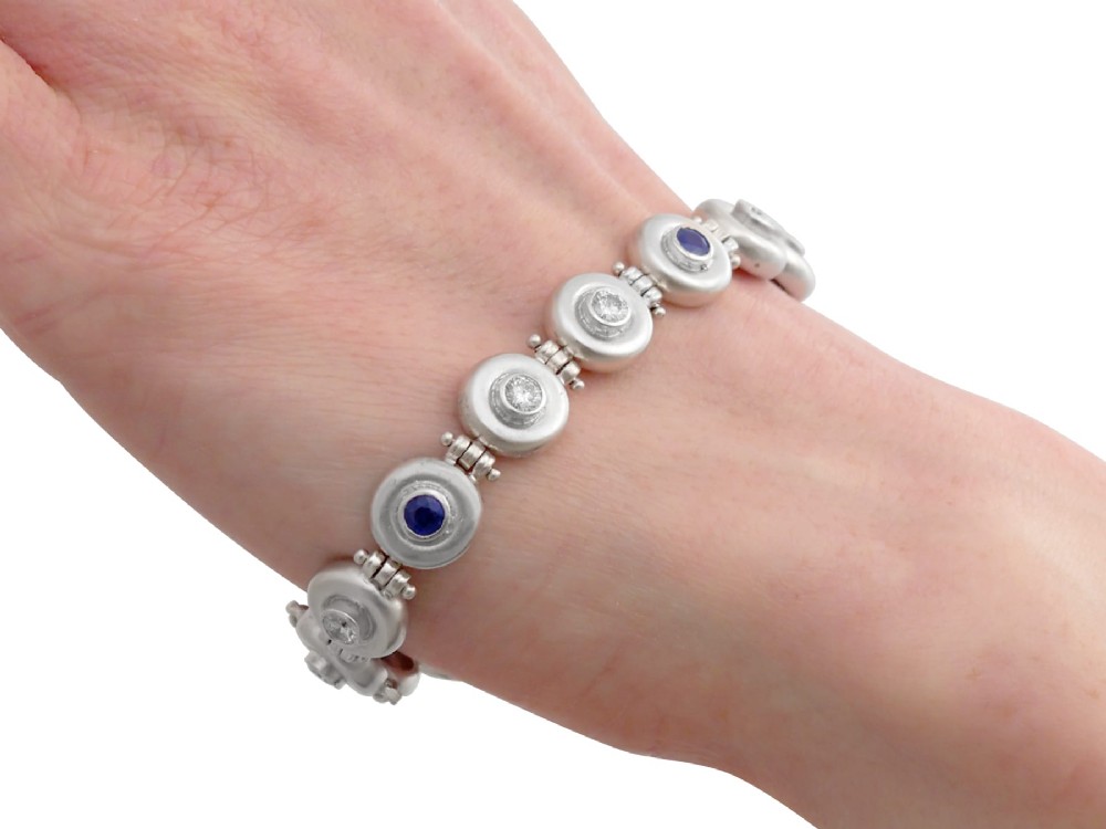 A vintage 18ct white gold articulated link bracelet set with alternating bezel-mounted round diamonds and blue sapphires. View XIV