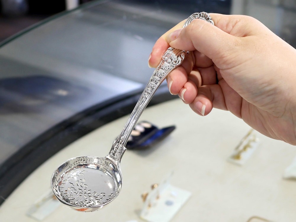 A collection of ornate sterling silver cutlery pieces featuring intricately embossed handles and polished bowls, including ladles, forks, knives, and spoons. View III