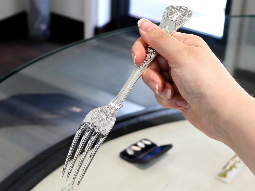 A collection of ornate sterling silver cutlery pieces featuring intricately embossed handles and polished bowls, including ladles, forks, knives, and spoons. View V