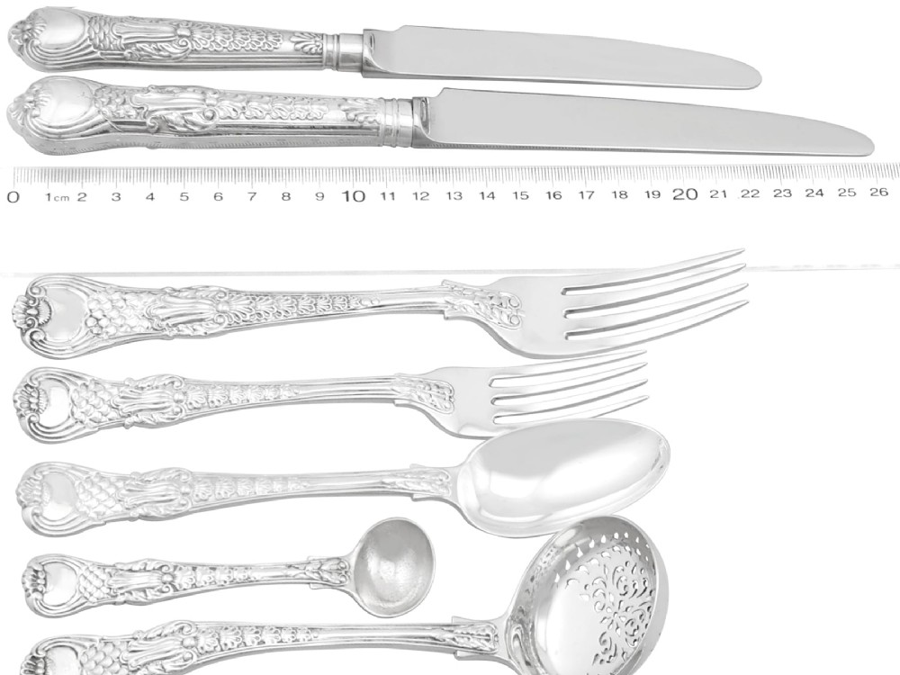 A collection of ornate sterling silver cutlery pieces featuring intricately embossed handles and polished bowls, including ladles, forks, knives, and spoons. View VII