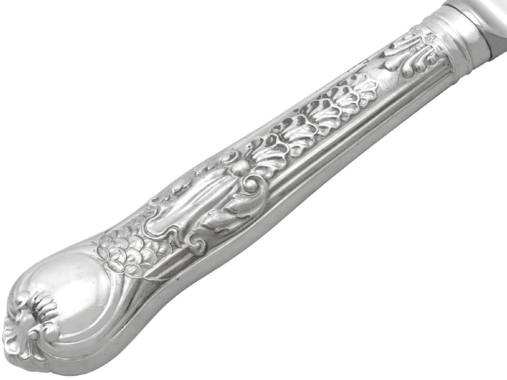 A collection of ornate sterling silver cutlery pieces featuring intricately embossed handles and polished bowls, including ladles, forks, knives, and spoons. View X