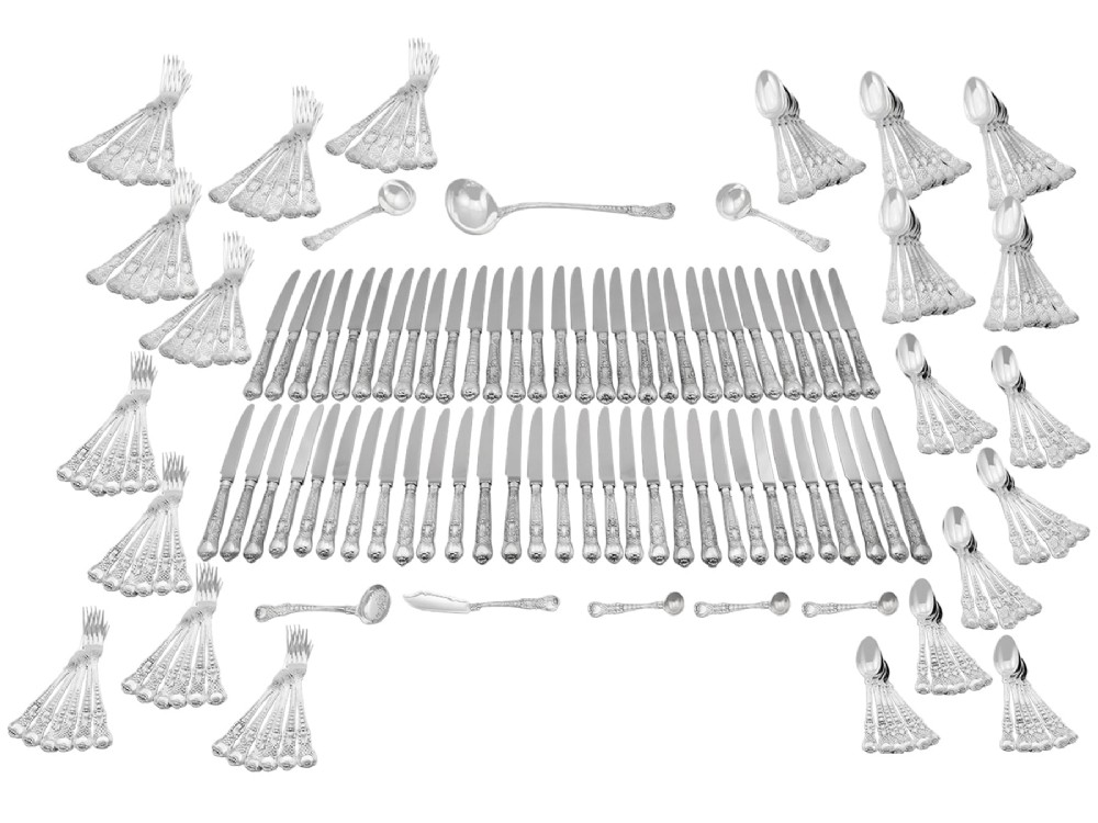 A collection of ornate sterling silver cutlery pieces featuring intricately embossed handles and polished bowls, including ladles, forks, knives, and spoons. View XV