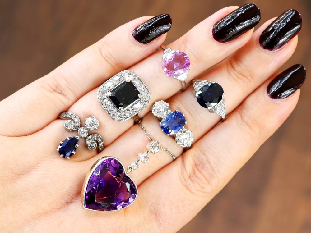 An Art Deco platinum cluster ring featuring a central rectangular blue sapphire surrounded by twelve old-cut diamonds with millegrain edges. View IV