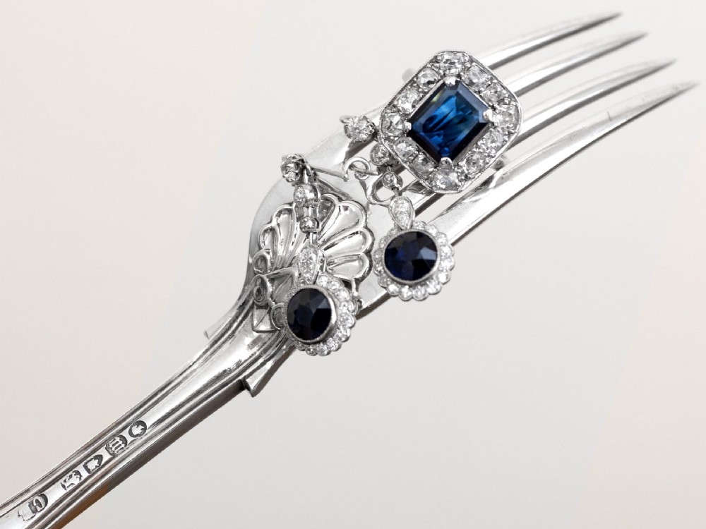An Art Deco platinum cluster ring featuring a central rectangular blue sapphire surrounded by twelve old-cut diamonds with millegrain edges. View VII