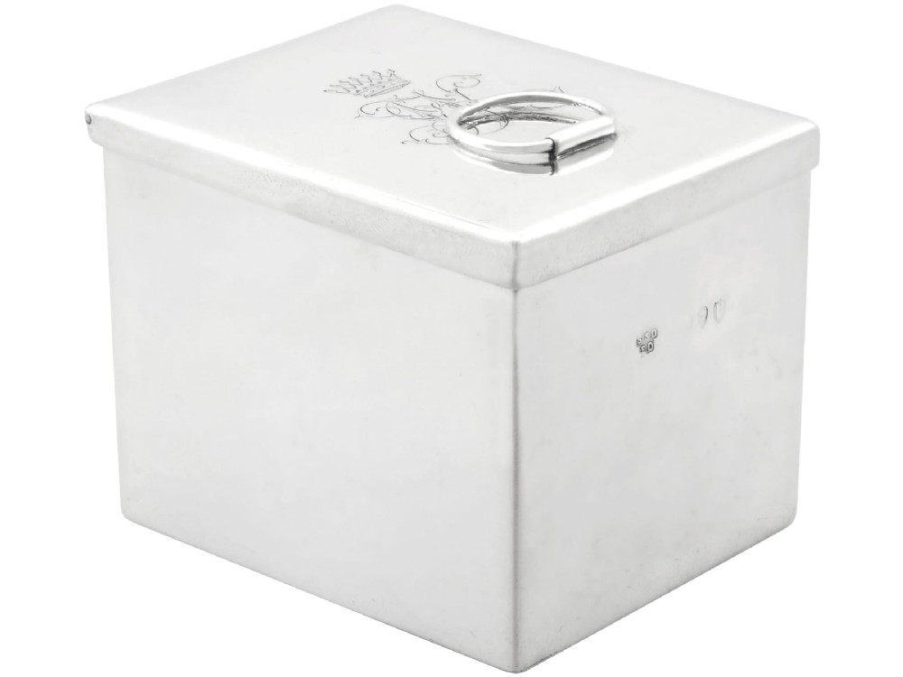 A rectangular Victorian sterling silver tea caddy featuring an engraved crest, top folding handle, and visible side hallmarks.