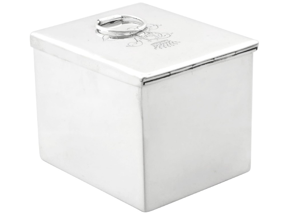 A rectangular Victorian sterling silver tea caddy featuring an engraved crest, top folding handle, and visible side hallmarks. View II