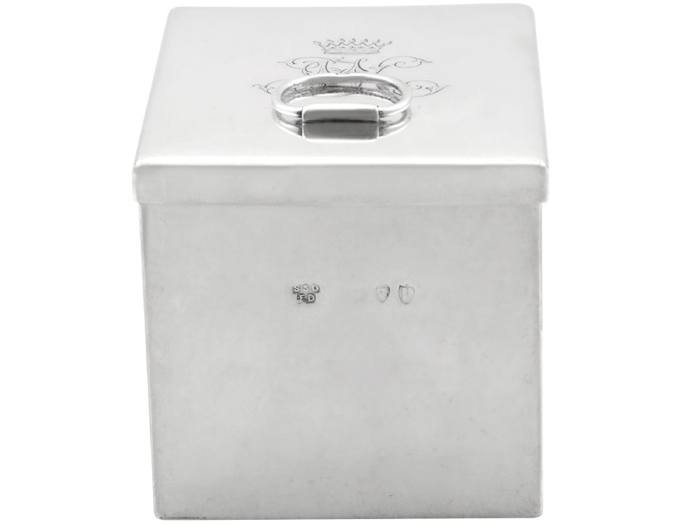 A rectangular Victorian sterling silver tea caddy featuring an engraved crest, top folding handle, and visible side hallmarks. View III