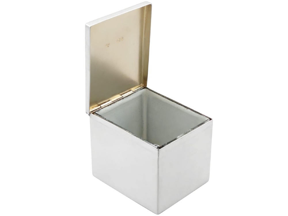 A rectangular Victorian sterling silver tea caddy featuring an engraved crest, top folding handle, and visible side hallmarks. View V