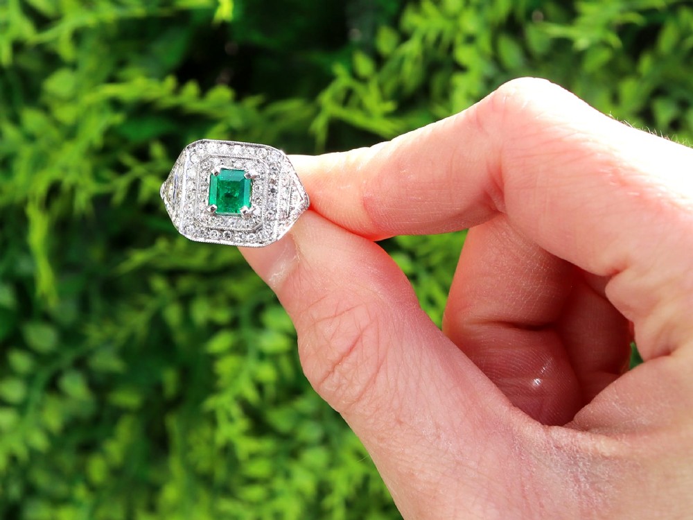 An Art Deco platinum ring featuring a central square green emerald surrounded by geometric concentric halos of brilliant-cut diamonds. View II