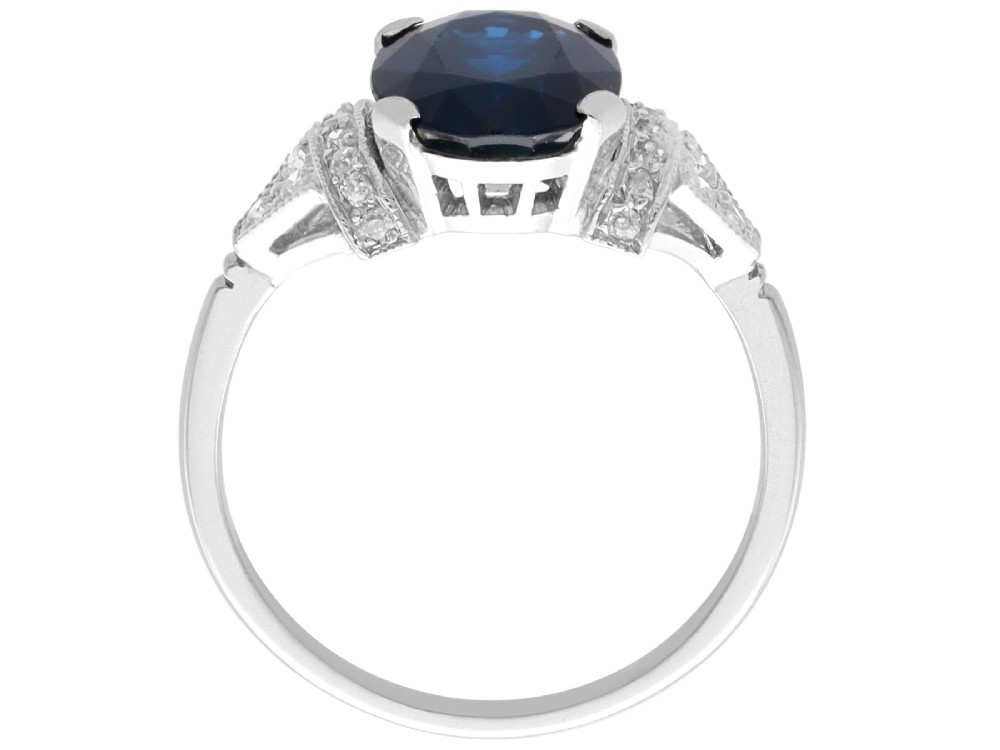 An Art Deco platinum ring featuring a centrally set oval blue sapphire flanked by diamond-set geometric shoulders. View VI