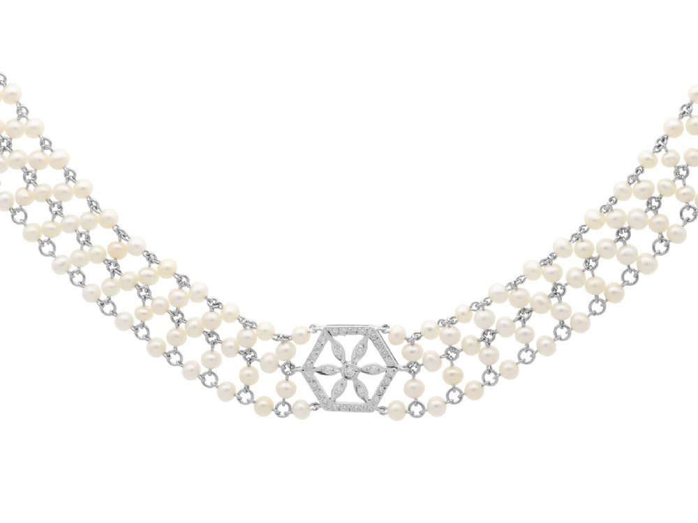 A multi-strand white pearl choker necklace joined at the front by an 18ct white gold hexagonal plaque set with small diamonds.