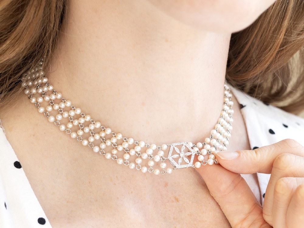 A multi-strand white pearl choker necklace joined at the front by an 18ct white gold hexagonal plaque set with small diamonds. View V