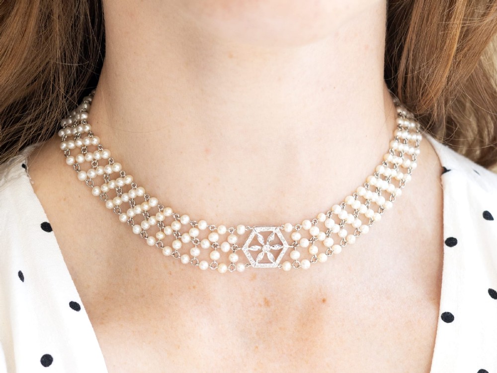 A multi-strand white pearl choker necklace joined at the front by an 18ct white gold hexagonal plaque set with small diamonds. View VI