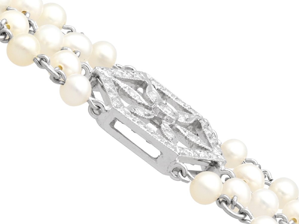 A multi-strand white pearl choker necklace joined at the front by an 18ct white gold hexagonal plaque set with small diamonds. View XI