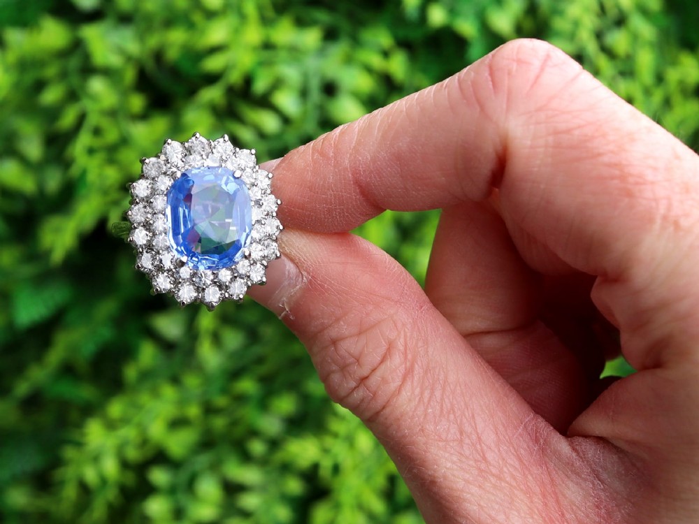 A vintage 14ct white gold cluster ring featuring a centrally mounted cushion-cut blue Ceylon sapphire surrounded by a double halo of round brilliant diamonds. View II