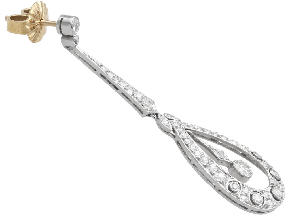 A pair of Art Deco platinum drop earrings featuring openwork teardrop frames set with diamonds and geometric articulated tops. View V