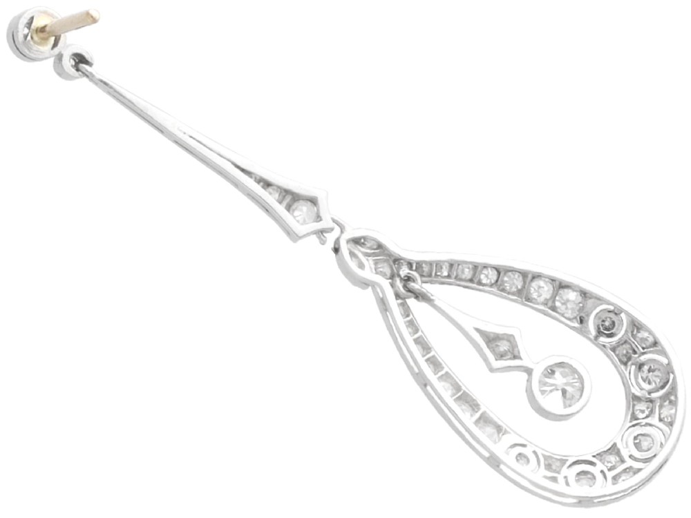 A pair of Art Deco platinum drop earrings featuring openwork teardrop frames set with diamonds and geometric articulated tops. View VI